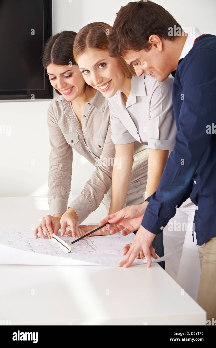 Three smiling architects working with a blueprint in their office Stock Photo