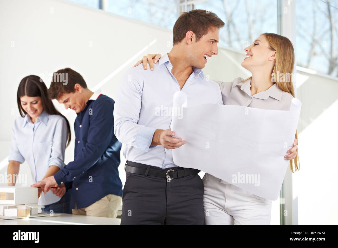 Happy couple with building plan for their new house in architecture office Stock Photo