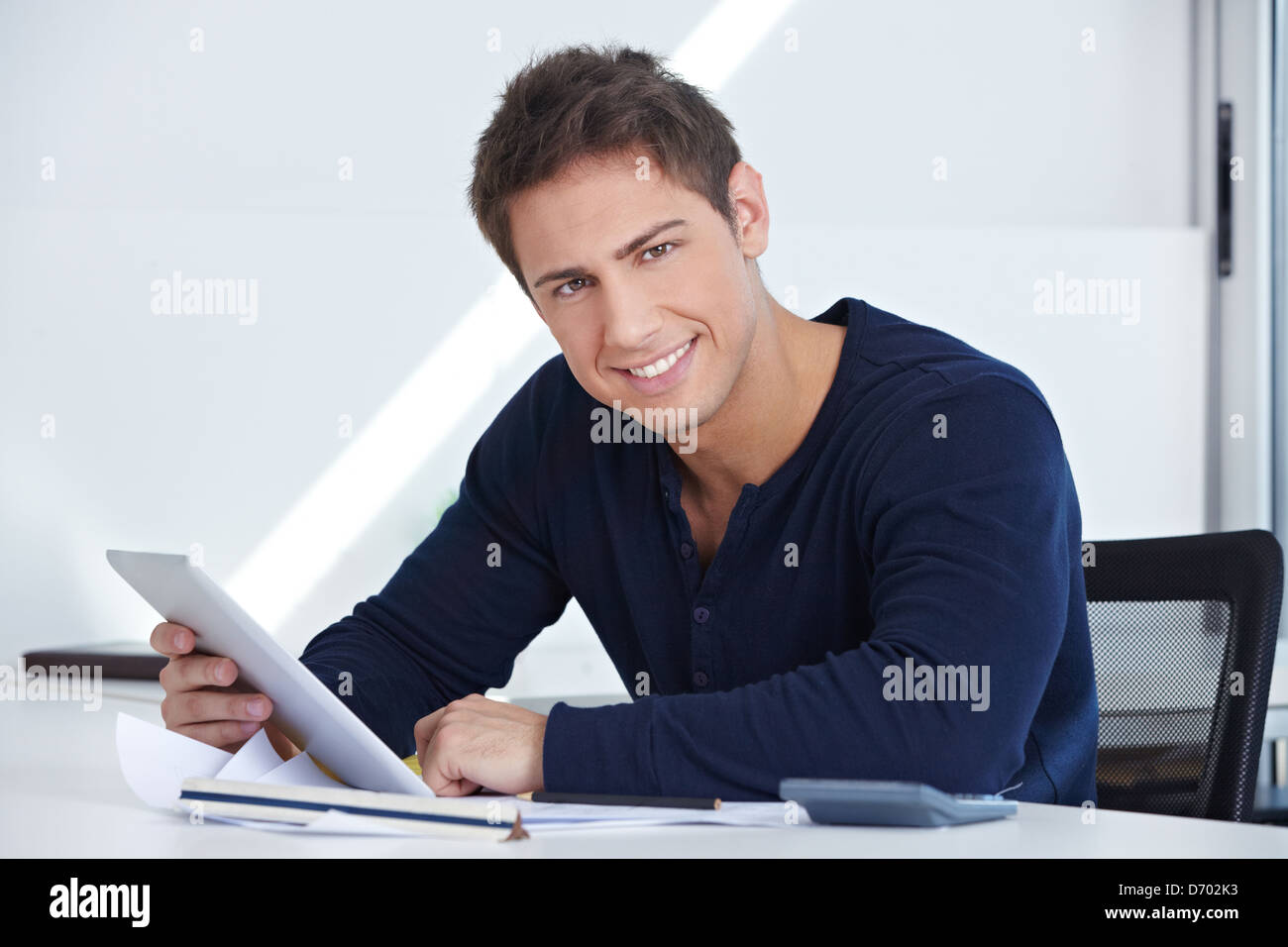 Happy designer sitting at his desk with a tablet computer in his hand Stock Photo