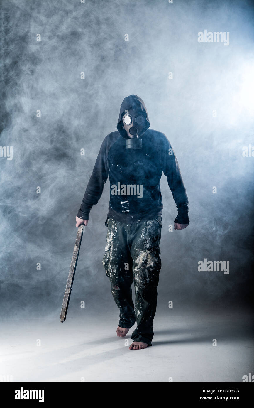 hooded figure in smoke wearing gas mask Stock Photo