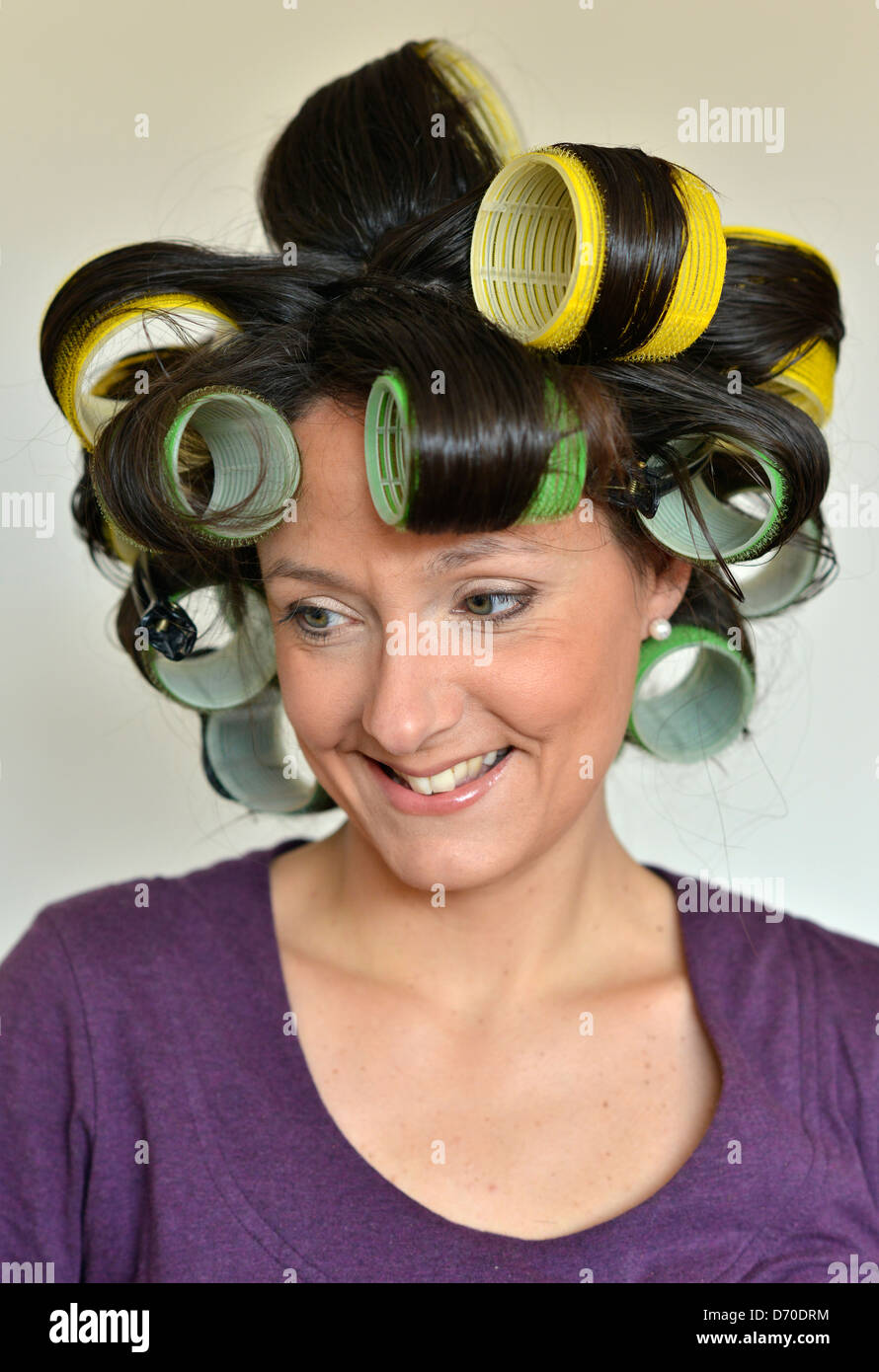 A lady in her thirties with dark brown hair wearing curlers. Stock Photo