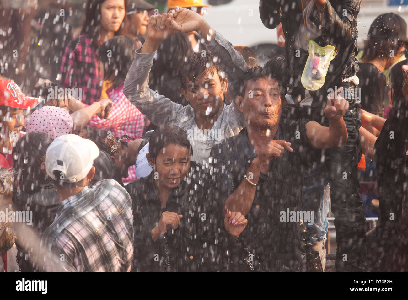 Young men dance in the street and get hosed with water during Mayanmar's Thingyan Water Festival. Stock Photo