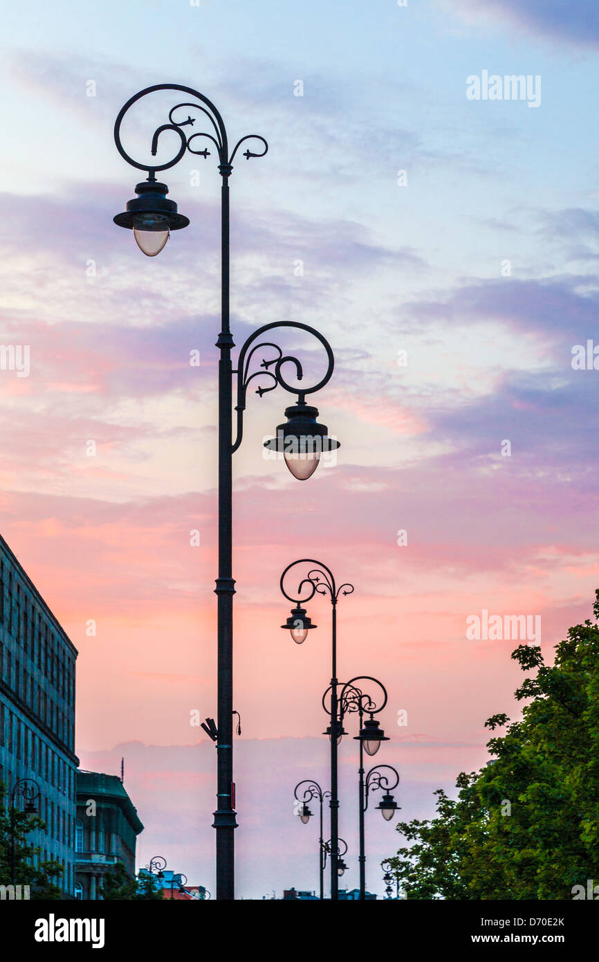 Silhouetted ornate street lights at sunset along the Krakowskie Przedmieście near Warsaw's Old Town. Stock Photo