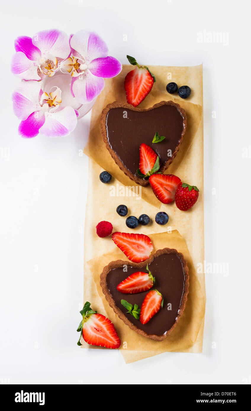 Delicious homemade chocolate tart with berries ornate with purple orchids. Stock Photo