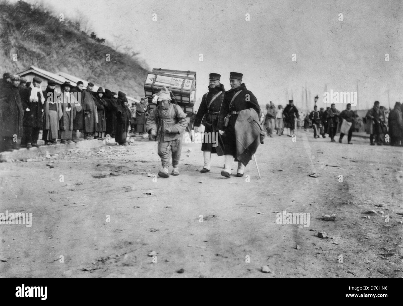 A Korean coolie carrying medical supplies from shore to hospital at Chemulpo, Korea during Russo Japanese War, 1904 Stock Photo