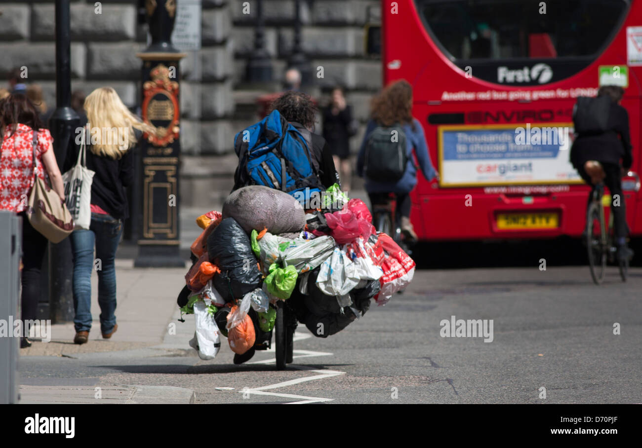 Tramp bag man bagman cycling through london weighed down with carrier bags Stock Photo