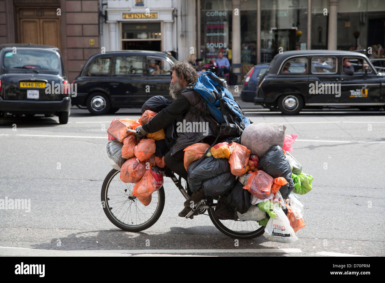 Tramp bag man bagman cycling through london weighed down with carrier bags Stock Photo