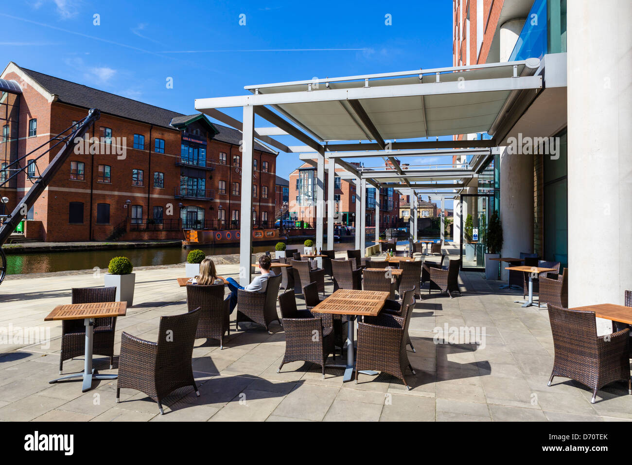 Couple siting on terrace of DoubleTree Hotel overlooking Leeds-Liverpool Canal, Granary Wharf, Leeds, West Yorkshire, UK Stock Photo
