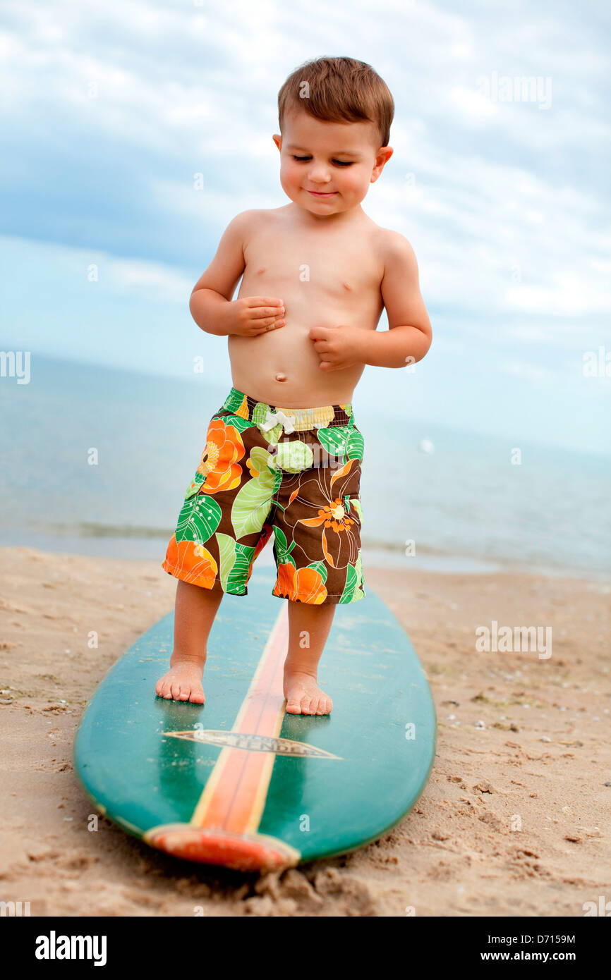 Boy standing on a surfboard on the beach, Glen Arbor, Leelanau County ...