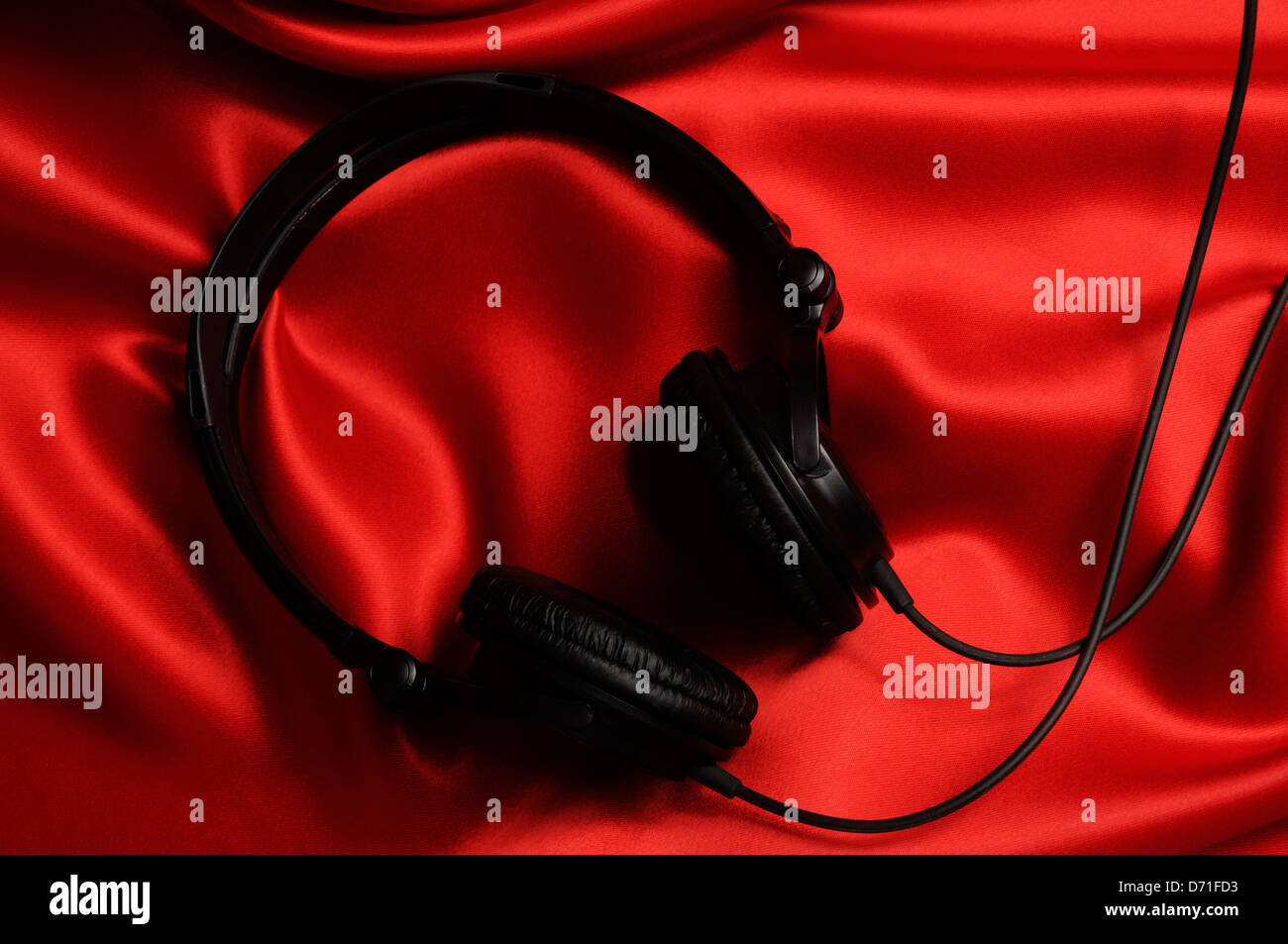 Headphones on red satin background. Stock Photo