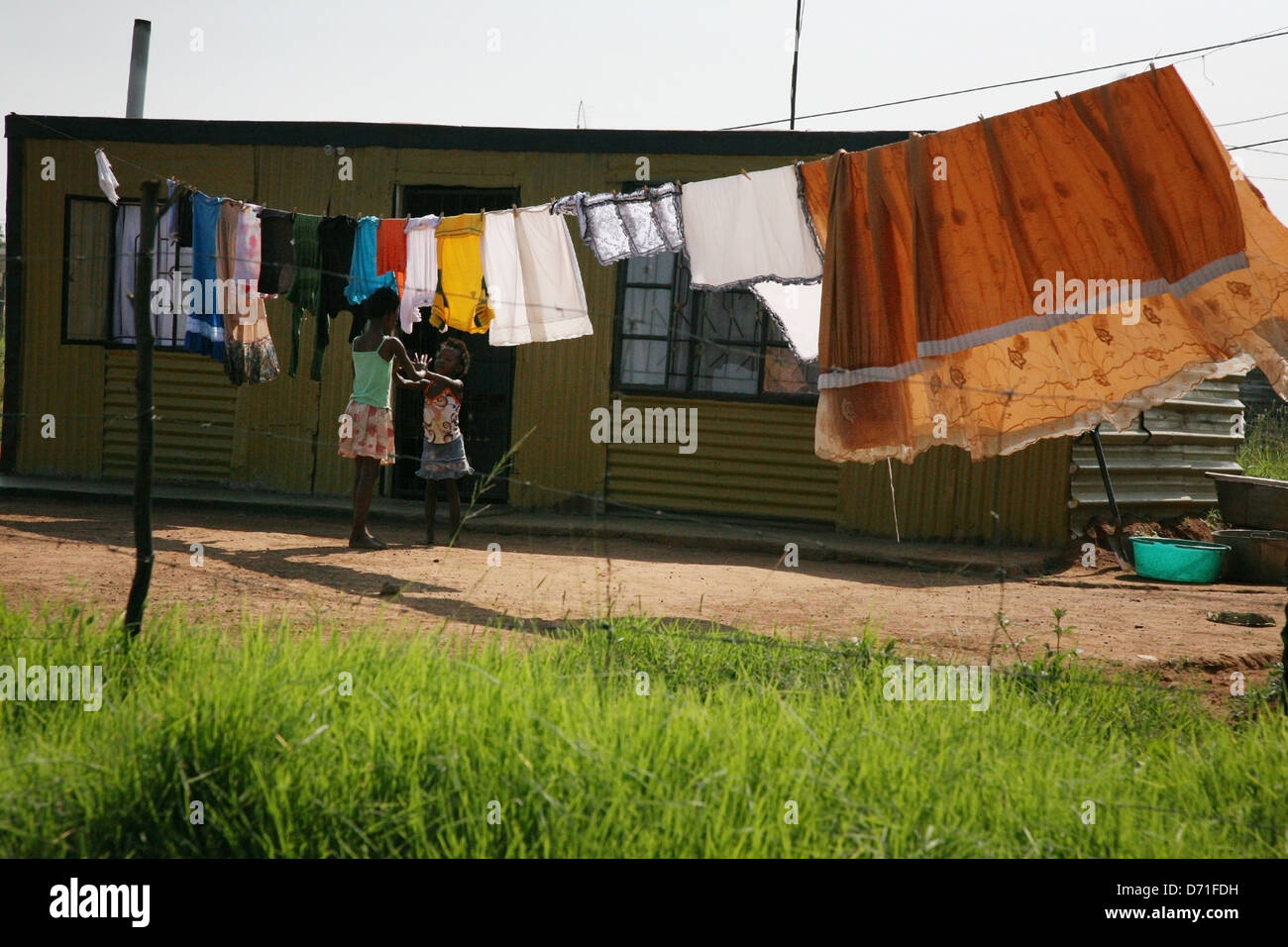 Young African girls play outside their tin shack home Stock Photo