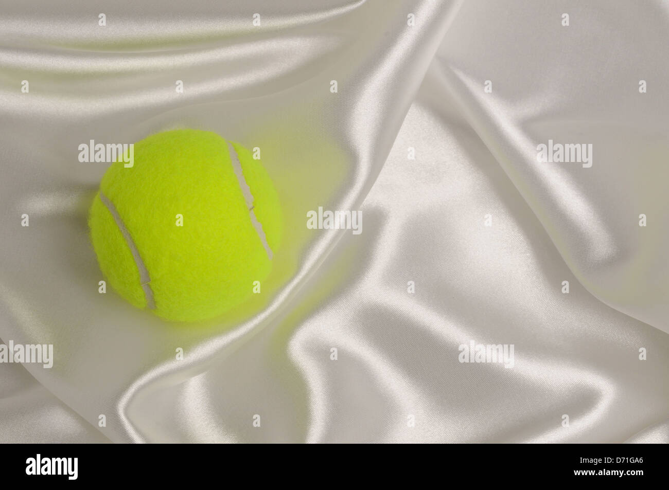 Tennis ball on white satin background. Stock Photo