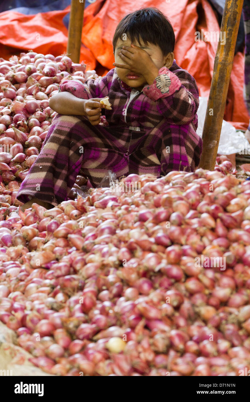 Shy little boy with scallions in Nyaung oo Market in Bagan, Myanmar Stock Photo