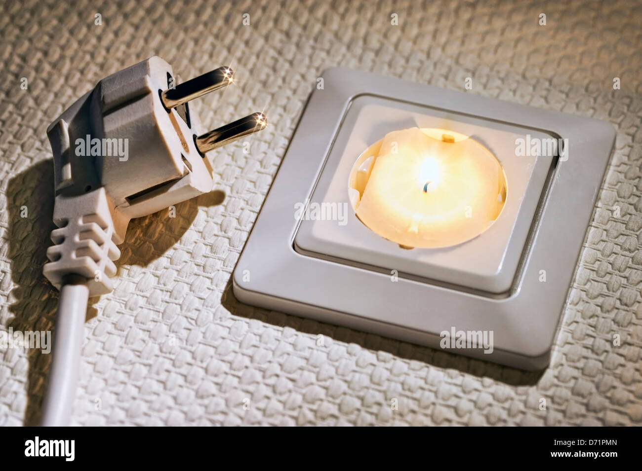 Outlet with burning candle, symbolic photo stream failure, blackout Stock Photo