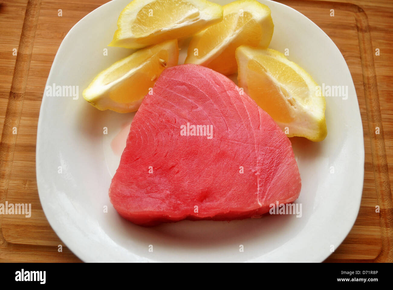 Raw Tuna Steak on a PLate with Lemon Stock Photo