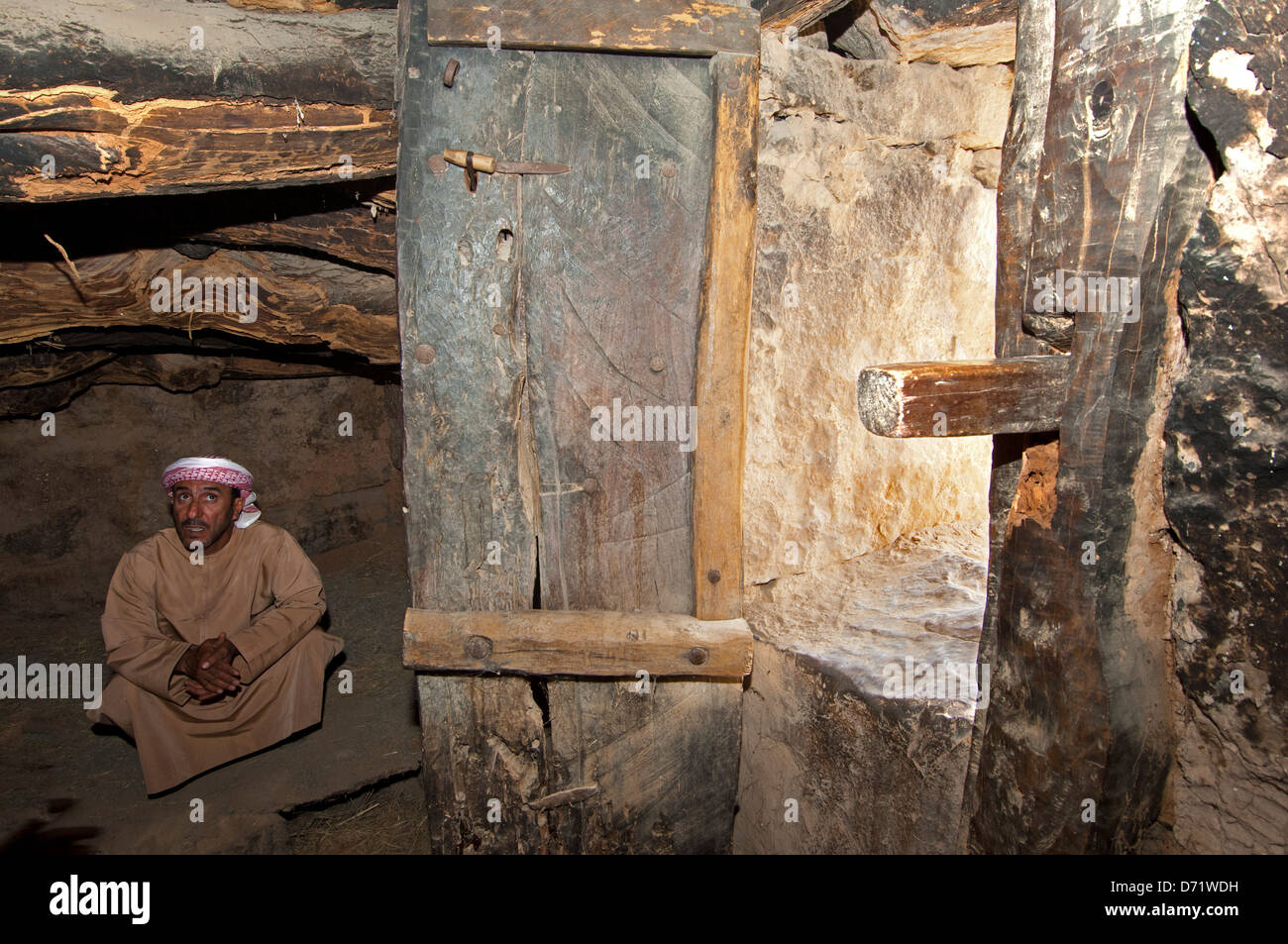 Arab man crouching on the floor of a Bedouin stone house, Musandam, Sultanate of Oman Stock Photo