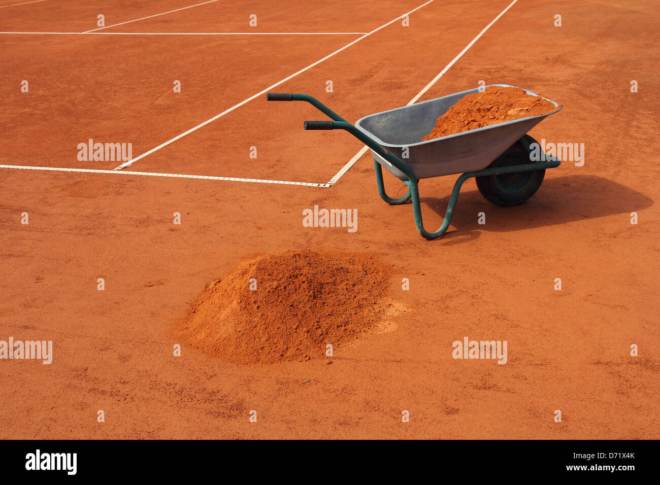 Wheelbarrow filled with red clay, on the tennis court Stock Photo