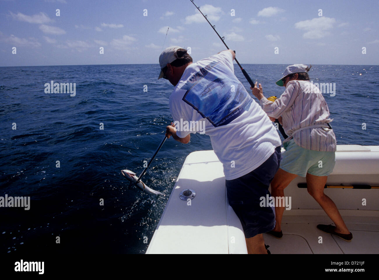 A man gaffs a King Mackerel (Scomberomorus cavalla) for a lady angler near Port Aransas Texas Stock Photo