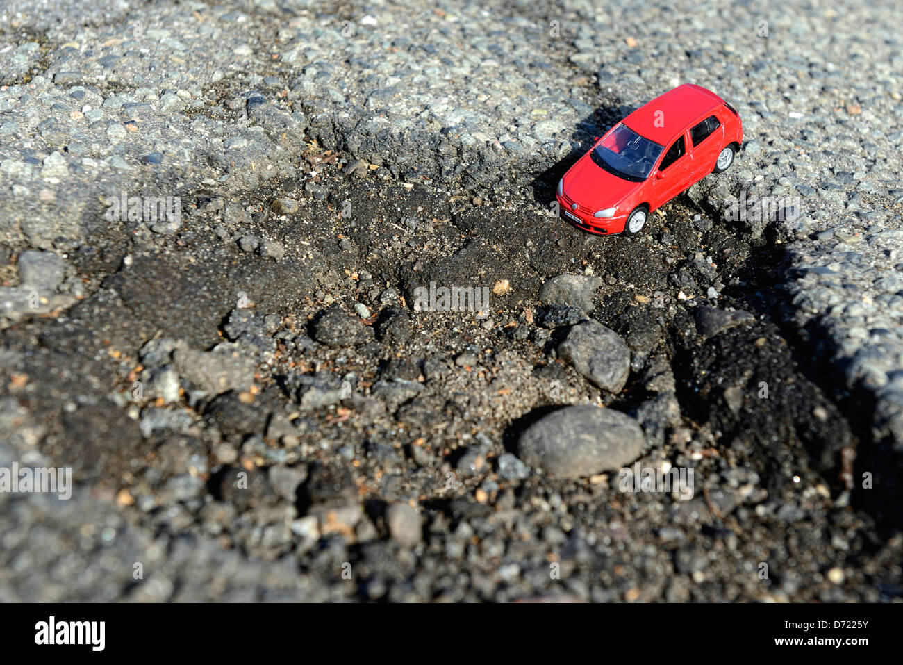Miniature car in blow hole on the street, symbolic photo street damages Stock Photo