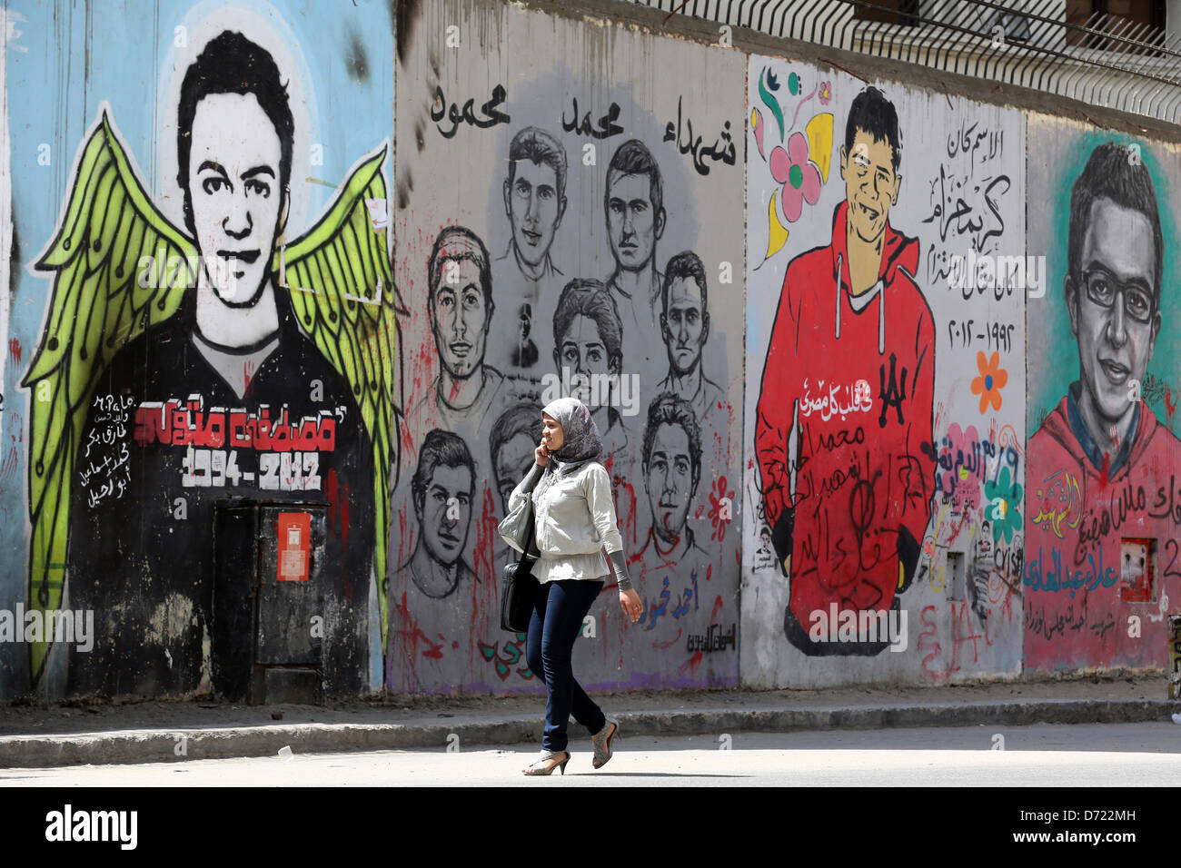 Woman walks in front of a revolutionary mural on a wall of martyrs near Tahrir Square in Cairo. Stock Photo