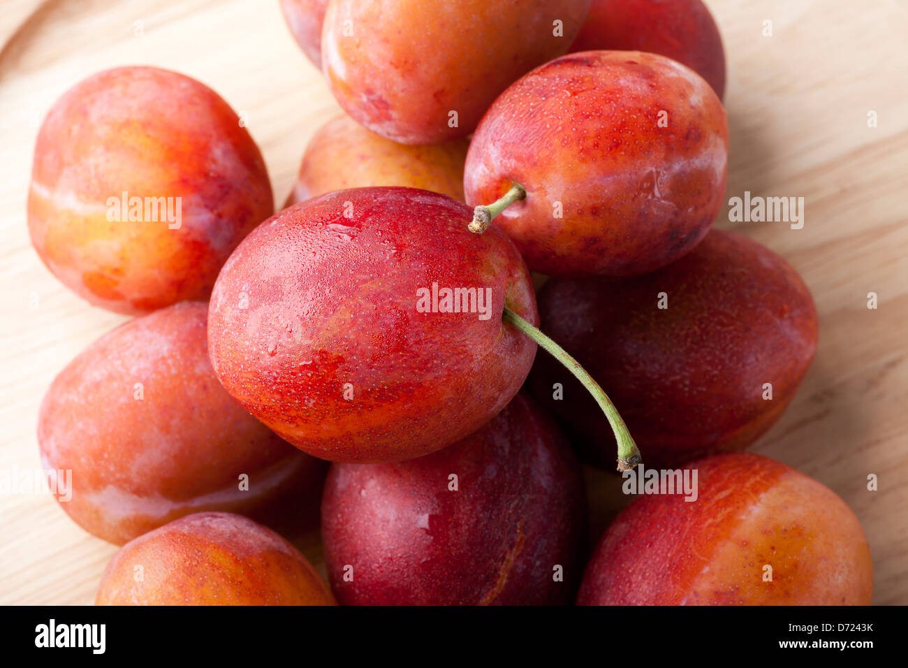 Fresh moist plums on wooden plate Stock Photo