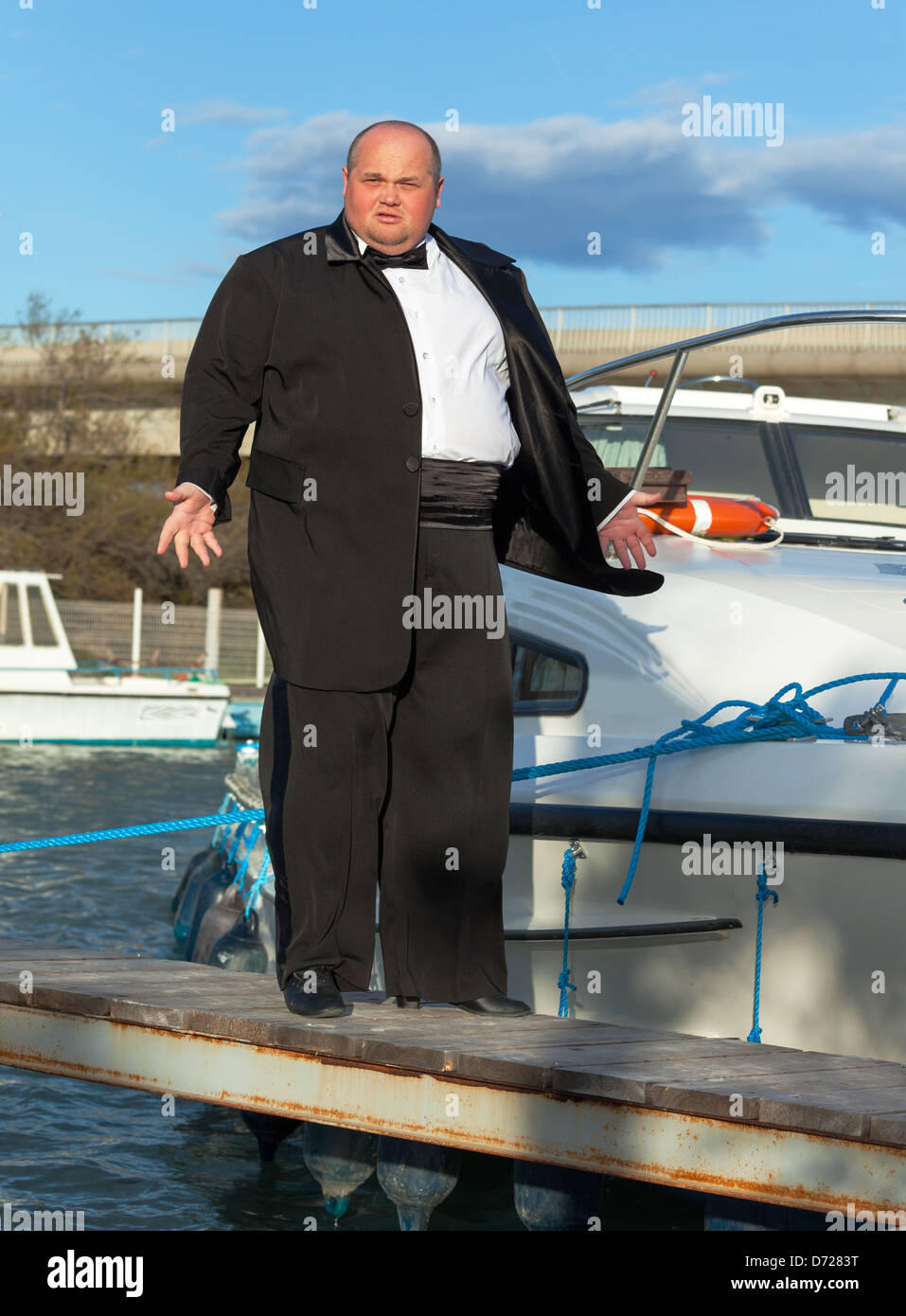 Overweight man in tuxedo standing on the deck of a luxury pleasure boat Stock Photo