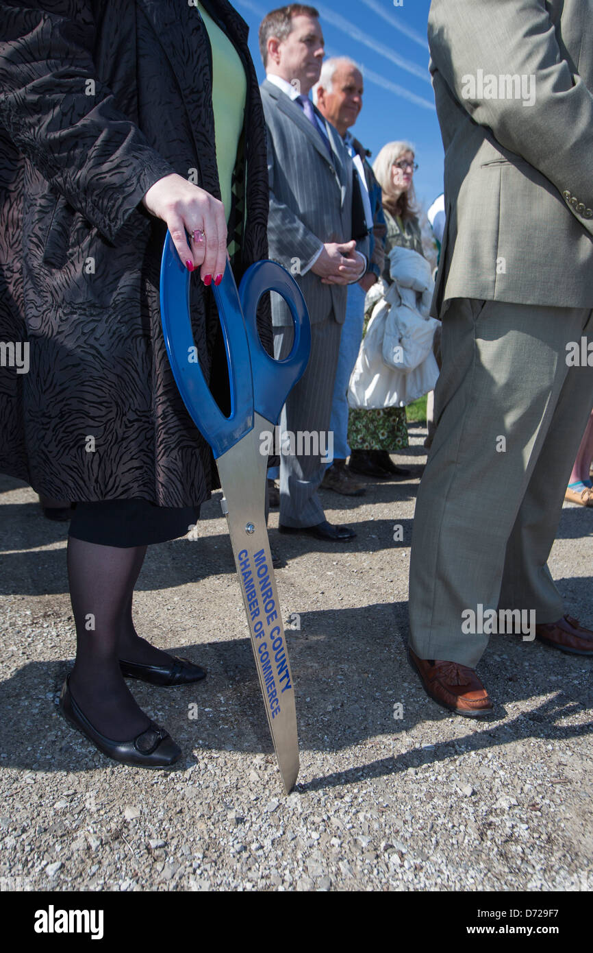 A representative of the Chamber of Commerce holds oversized scissors for a ribbon-cutting ceremony at a solar power project Stock Photo