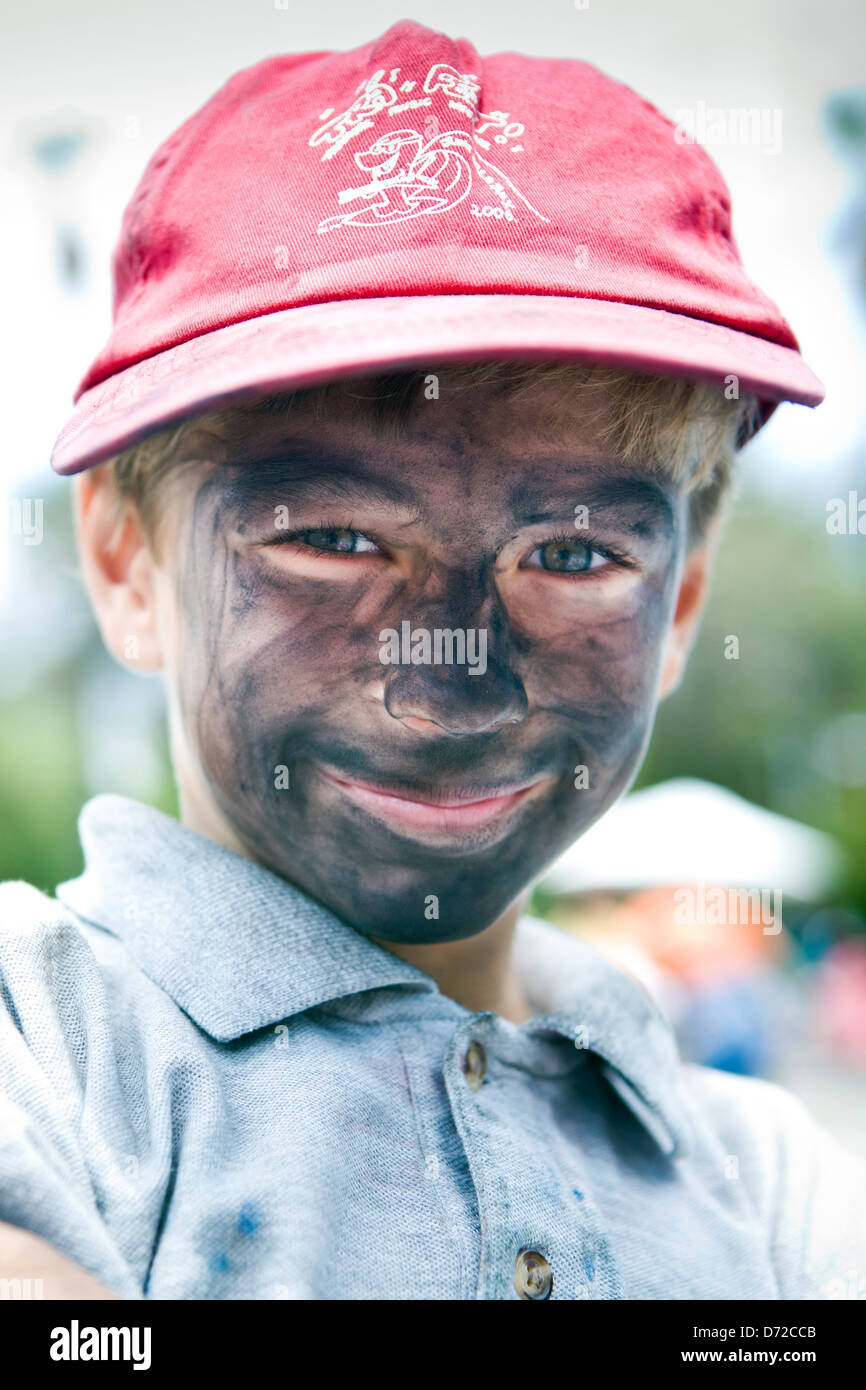 A boy with chalk smeared on his face at the I Madonnari street painting festival in California Stock Photo