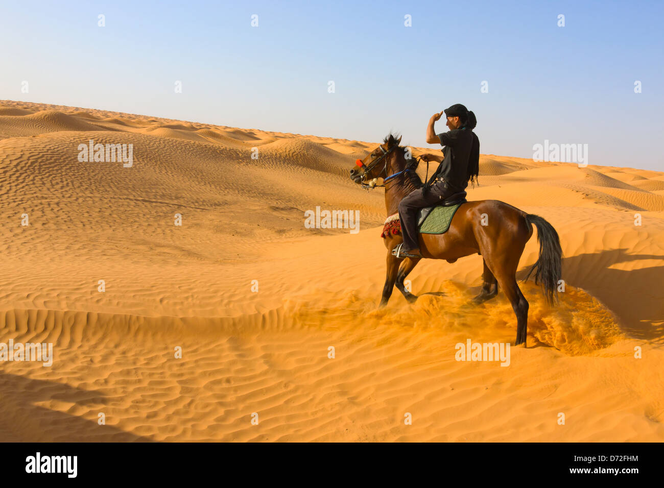 Man riding on horse in Sahara Desert, Ksar Ghilane, Tunisia Stock Photo