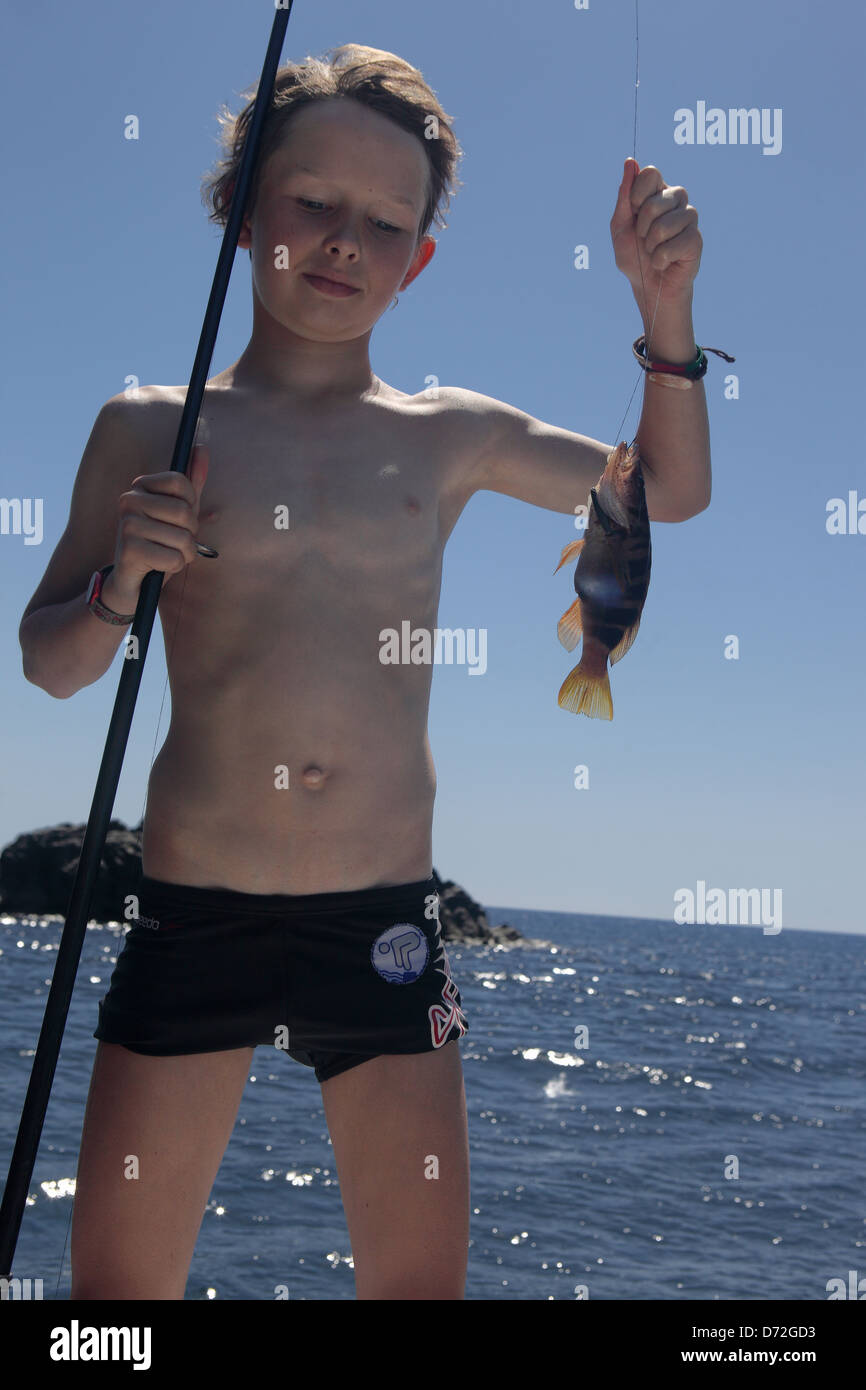 Alicudi, Italy, the boy has caught a fish from the sea Stock Photo
