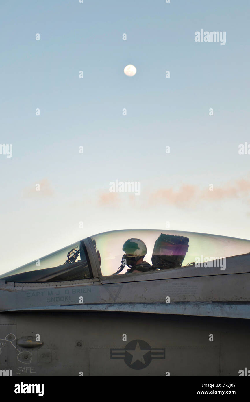 A US Navy F/A-18C Hornet fighter pilot prepares to take off during evening flight operations on the aircraft carrier USS Nimitz April 23, 2013 in the Pacific Ocean. Stock Photo