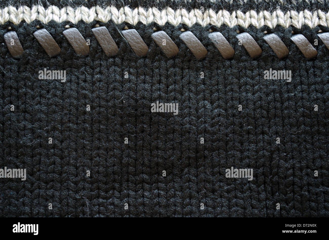 wool knit sweater texture decorated with leather stitch. white grey and black colors background closeup Stock Photo