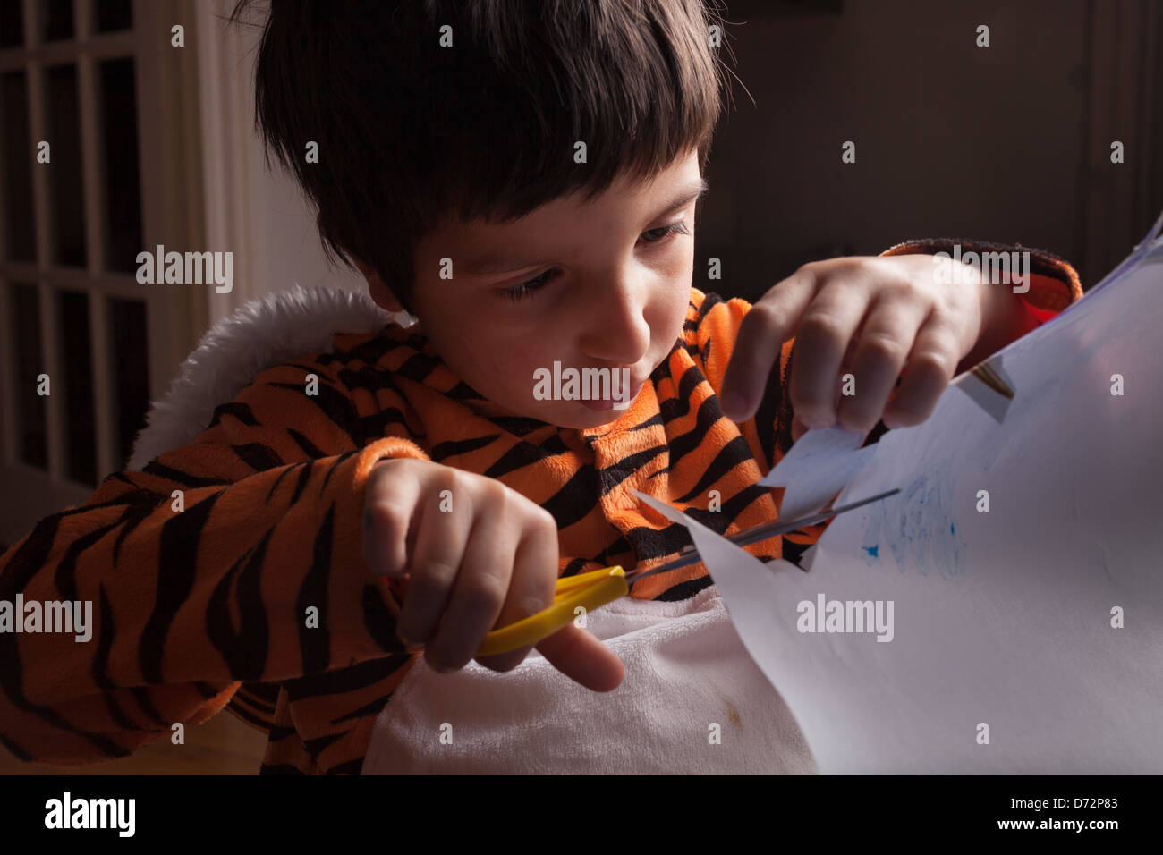 young boy in tiger costume cutting paper,World books day,London,UK Stock Photo
