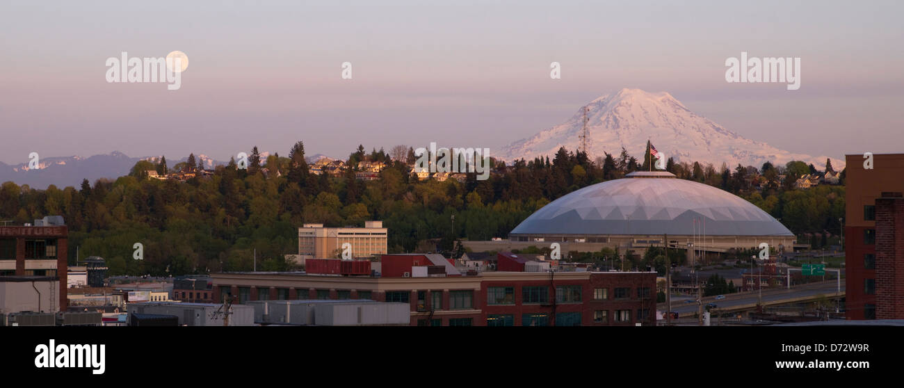 A full moon appears on the horizon near Mt Rainier and the Dome