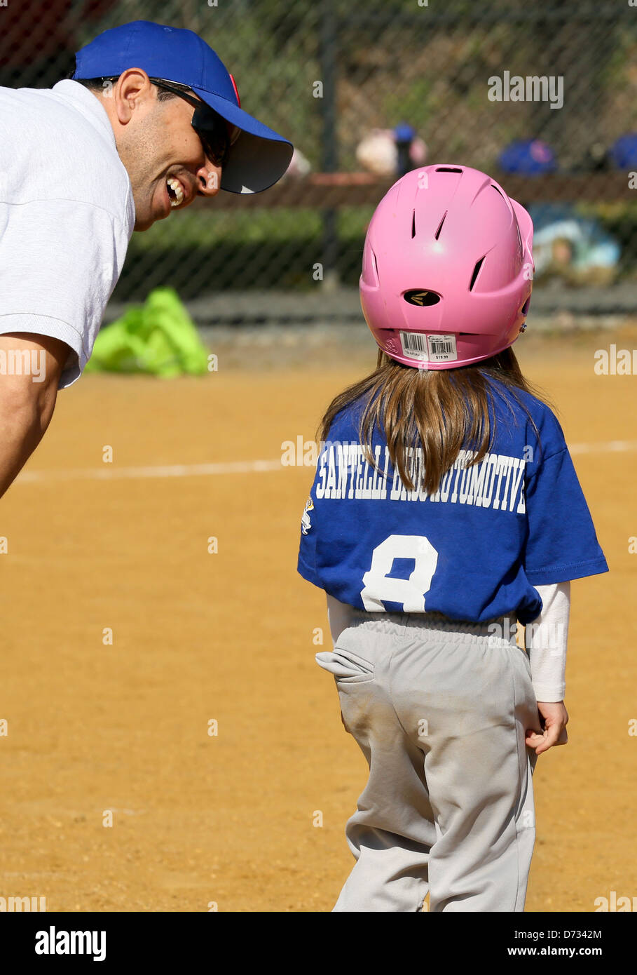 A little girl baseball player on first base getting encouragement from