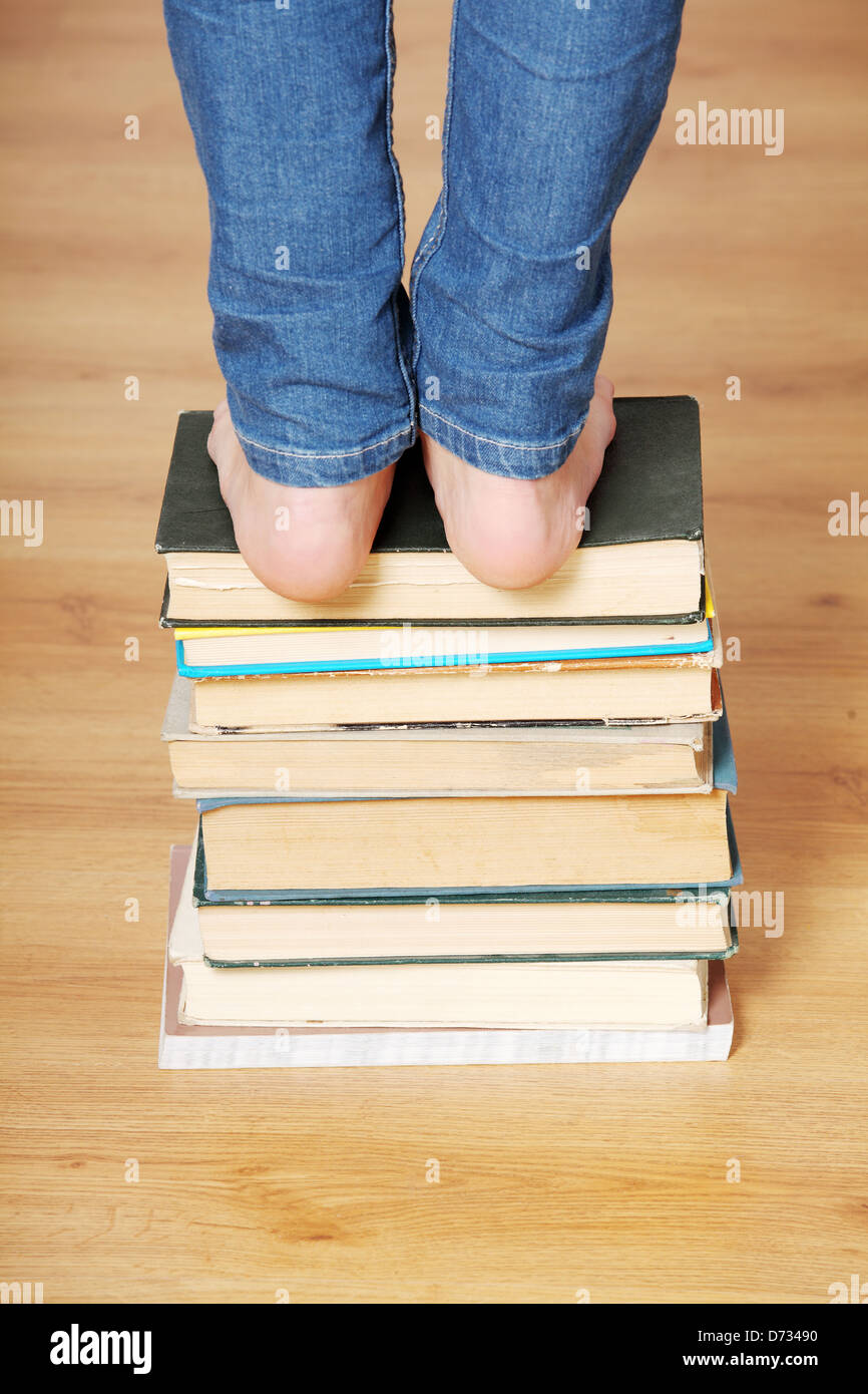 Girl standing on pile of books Stock Photo - Alamy