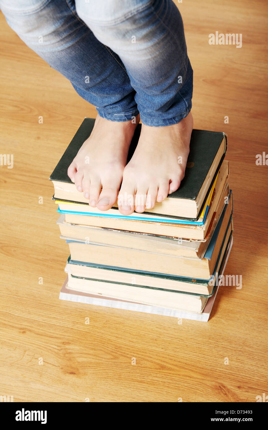 Girl standing on pile of books Stock Photo - Alamy
