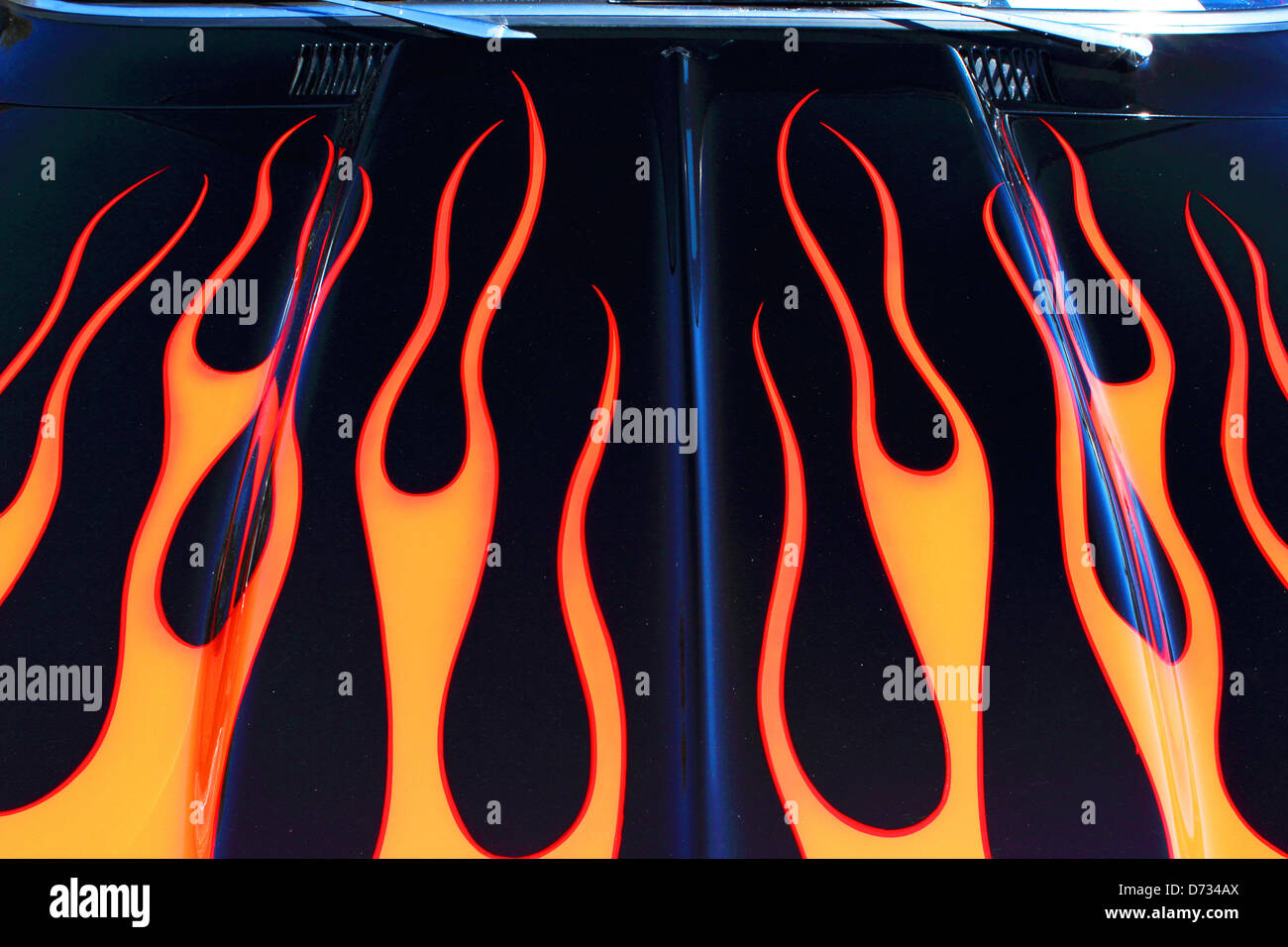 A flame design paint job adorns the hood of a classic car. Stock Photo