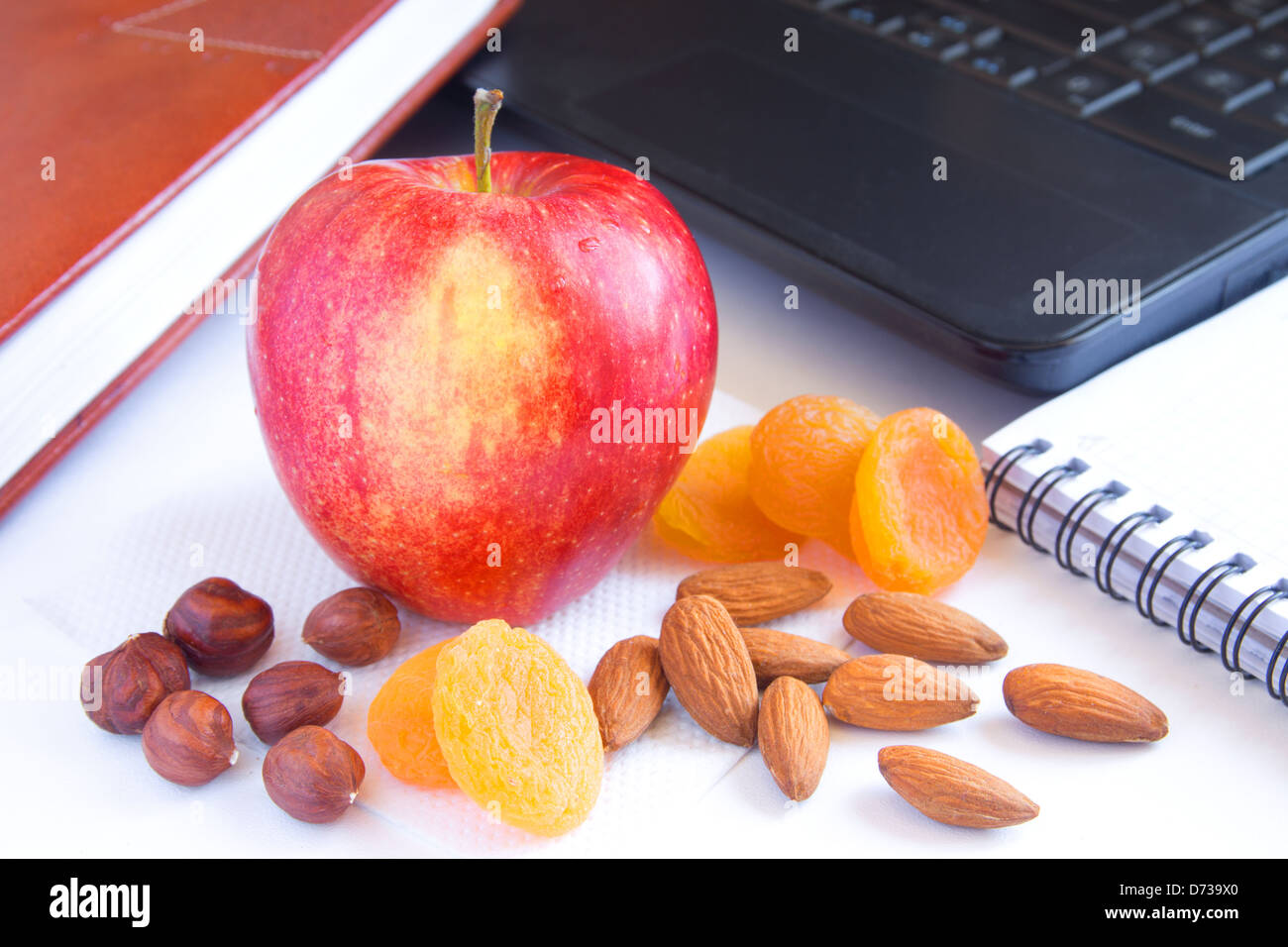 Healthy quick snack (lunch) in office. Red apple, dry fruits (apricots