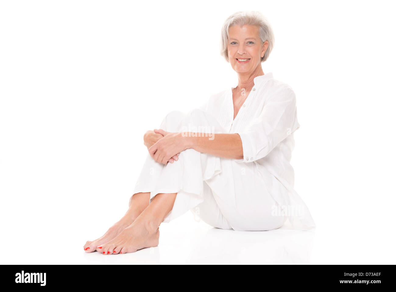 Sitting senior woman in front of white background Stock Photo