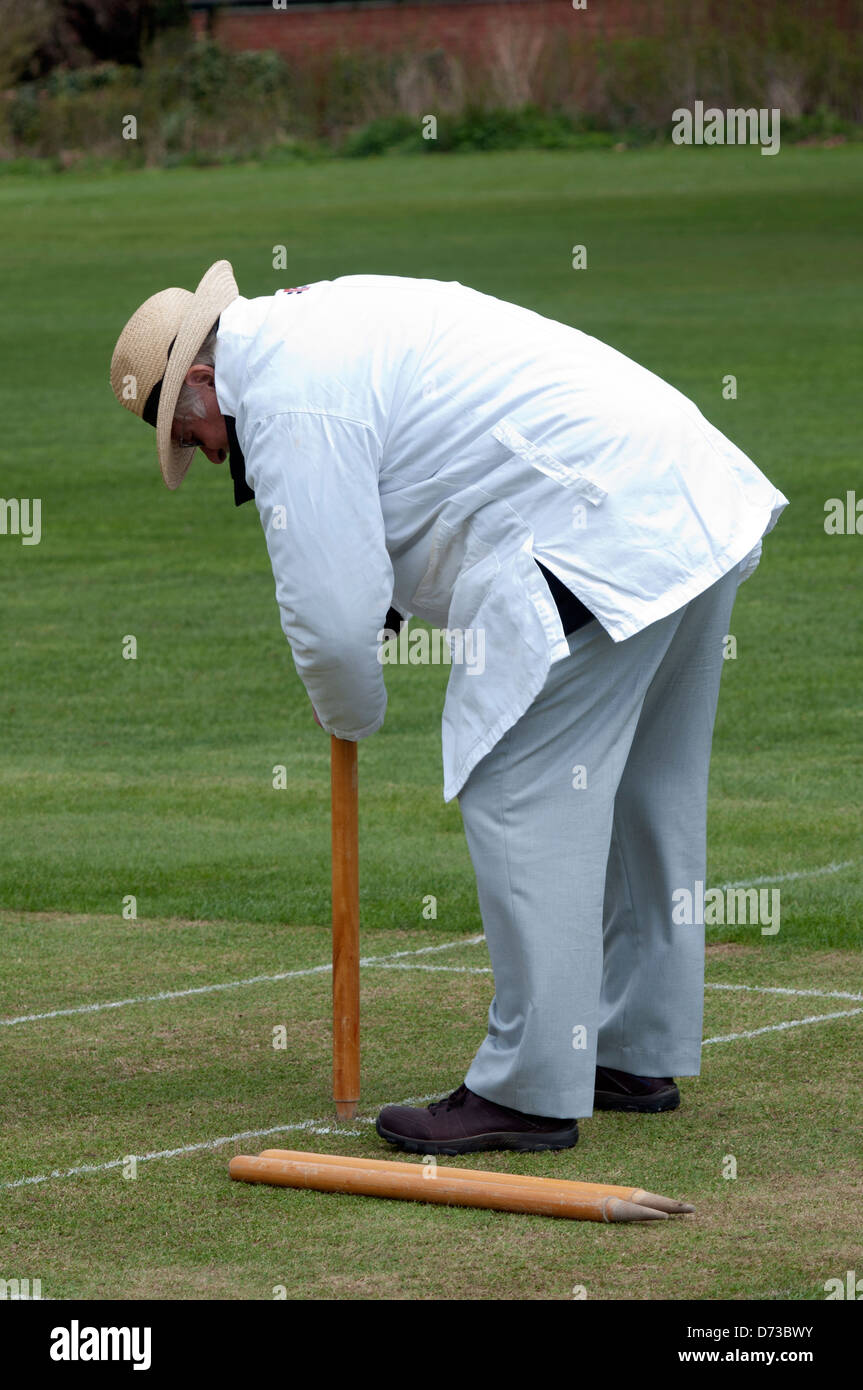 Village cricket at Leek Wootton, the umpire putting the wickets in. Stock Photo