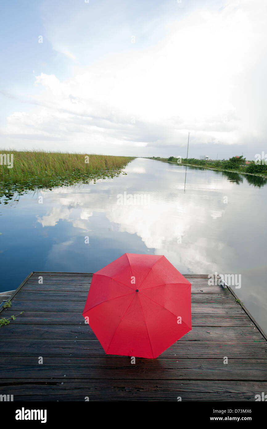 a red umbrella on a deck at a lake Stock Photo
