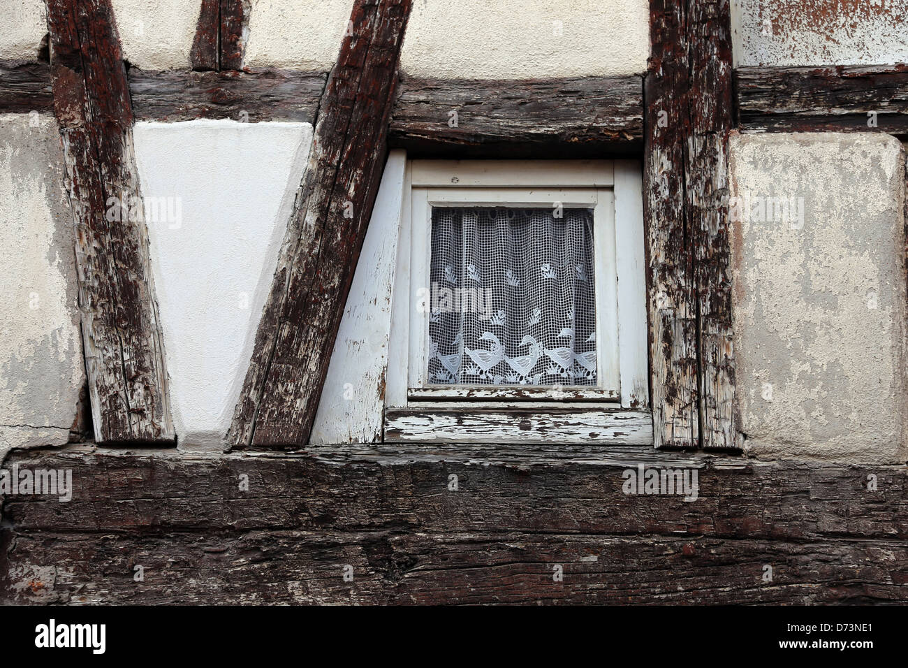 Half-timbered house with small window and ornamental curtain Stock Photo