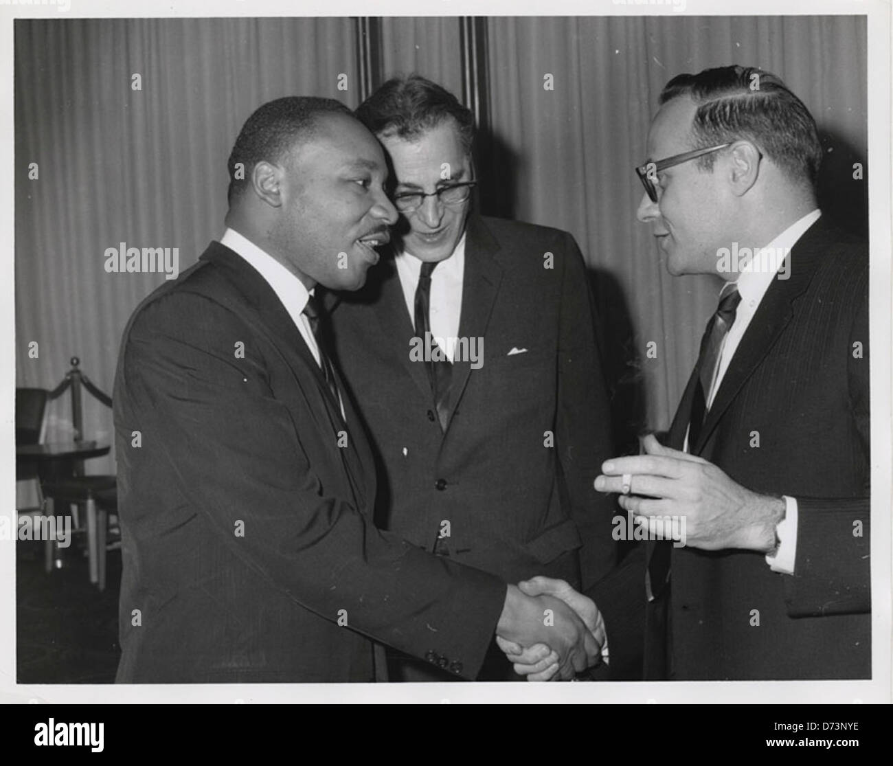 Martin Luther King, Jr. talking with Shad Polier while shaking hands with unidentified smoking man at American Jewish Congress fundraising event Stock Photo