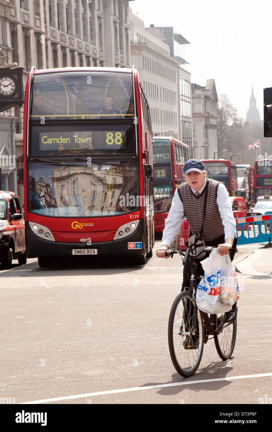 A male cyclist cycling his bicycle in Piccadilly Circus with London buses and traffic, Central London W1, UK Stock Photo