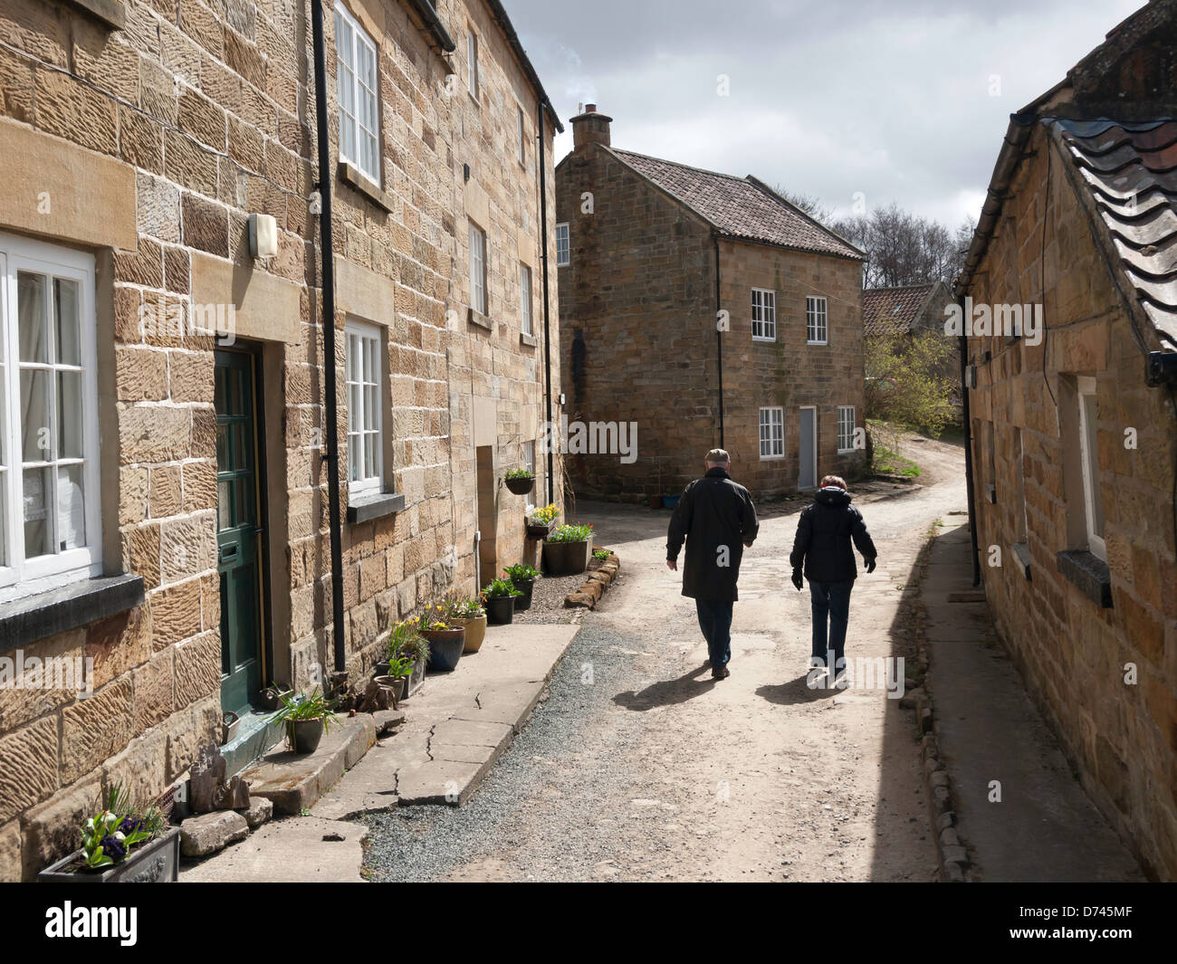 A couple walk briskly through High Mill at the North end of the Farndale walk in North Yorkshire famous in spring for daffodils Stock Photo