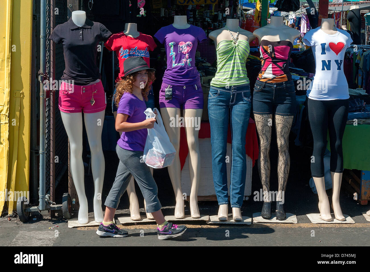 A young girls passing by clothed mannequins at Davis, California swapmeet. Stock Photo