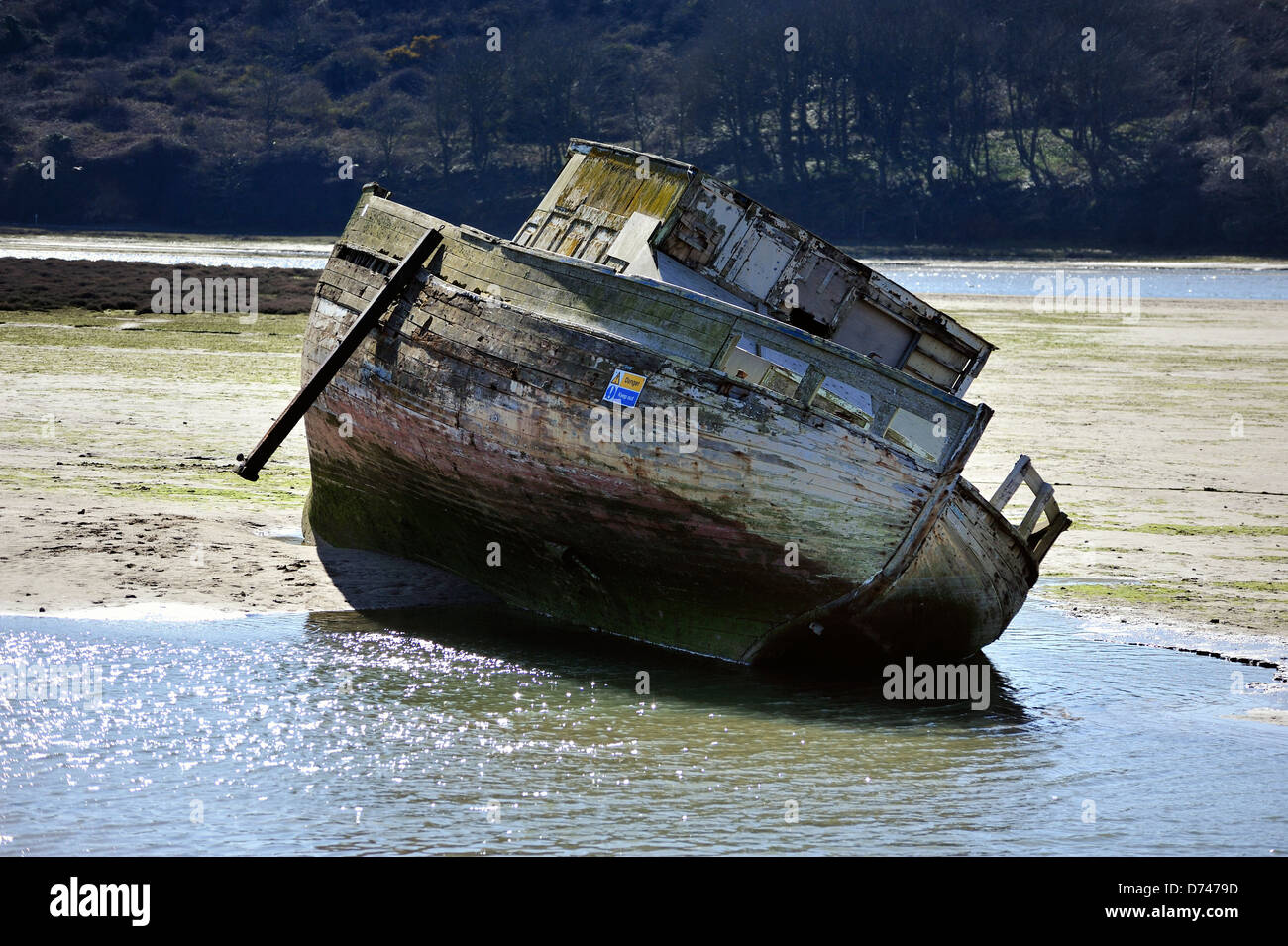Old derelict boat slowly rotting in an estuary at low tide Stock Photo