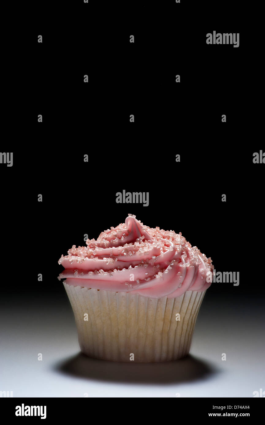 Pink iced cupcake on black background. Stock Photo