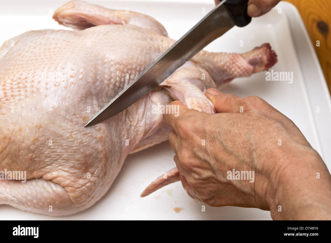 Hand with knife cutting chicken meat Stock Photo